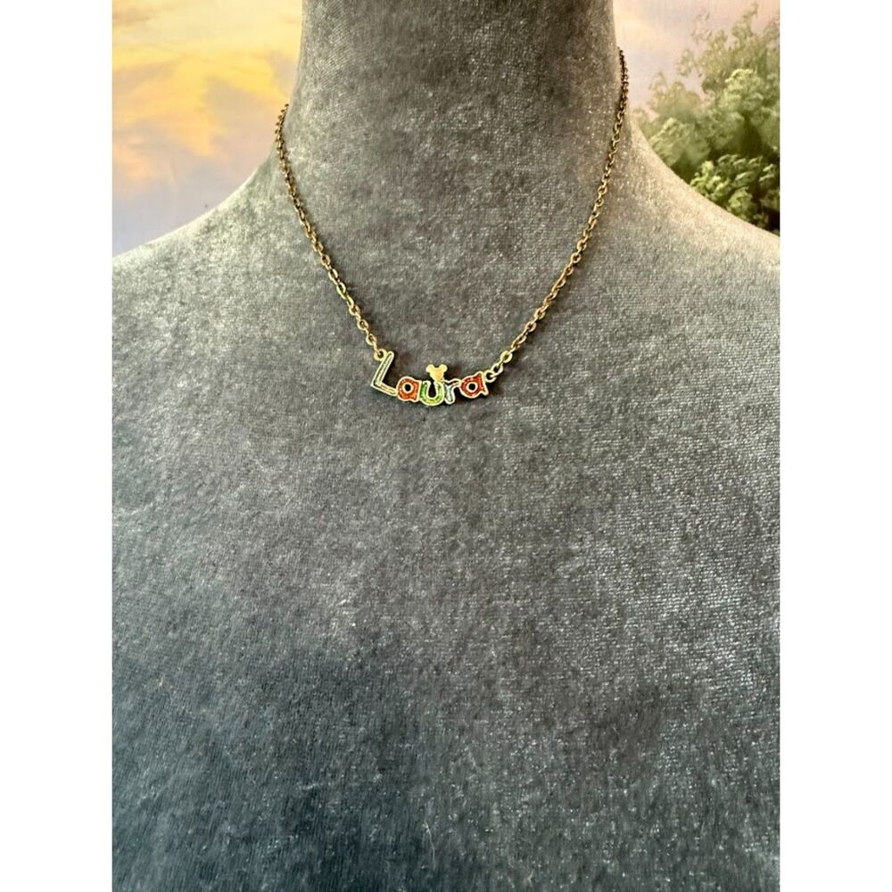 "Laura"with colorful, stylized lettering on a gold-toned chain